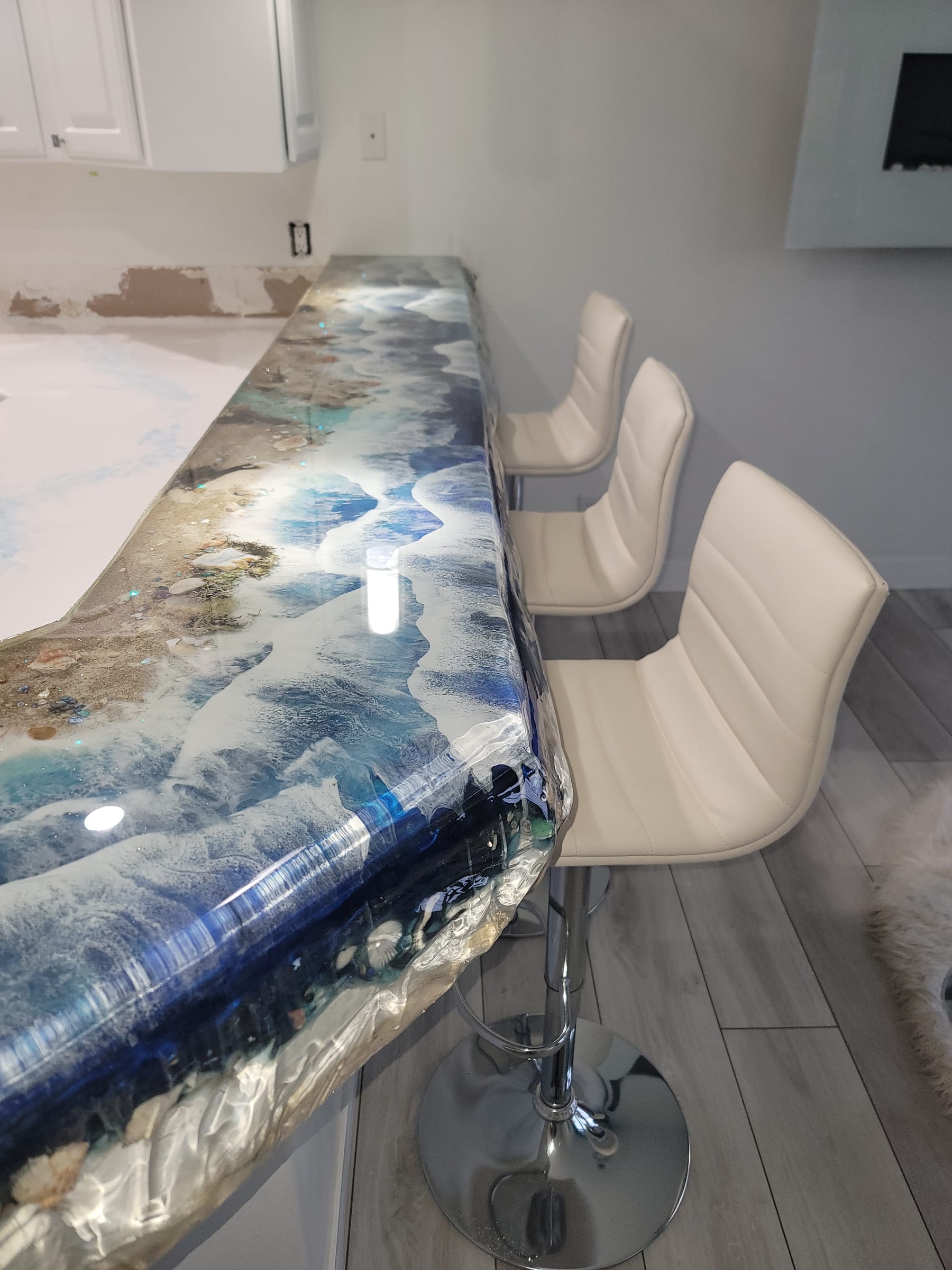 Close detail of a beach-themed epoxy bar top with embedded shells by Ray Sample